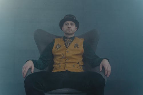 Free A Man in a Hat Sitting on Chair Stock Photo