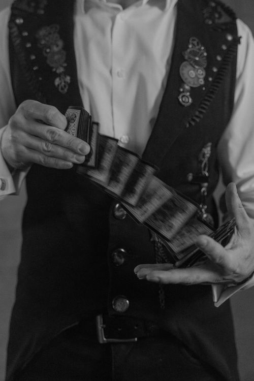 Free A grayscale image capturing a close-up of a magician performing a card trick. Stock Photo