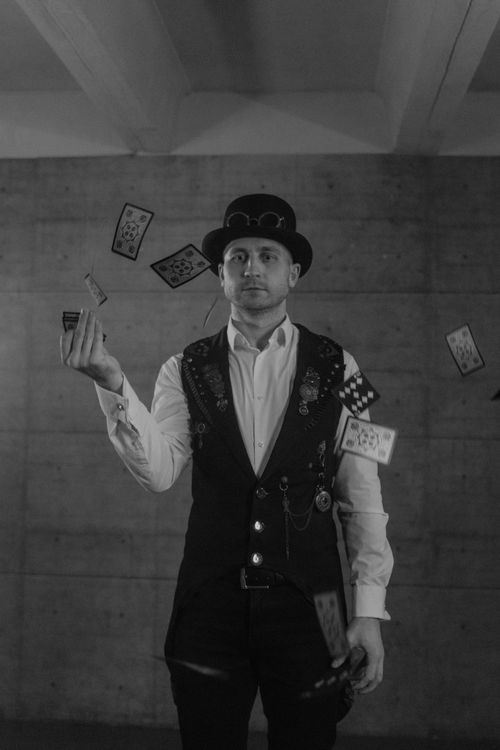 Free A magician in a vintage vest performs card tricks in a black and white photo. Stock Photo