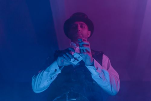 Free A magician showcases a captivating card trick under colorful lighting, creating an aura of mystery. Stock Photo