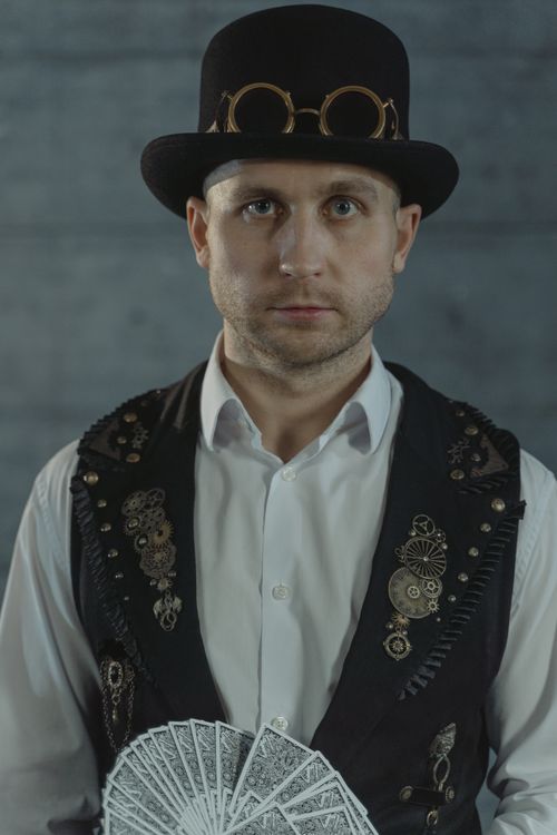 Free A mysterious magician in steampunk attire holding cards, evoking intrigue and magic. Stock Photo