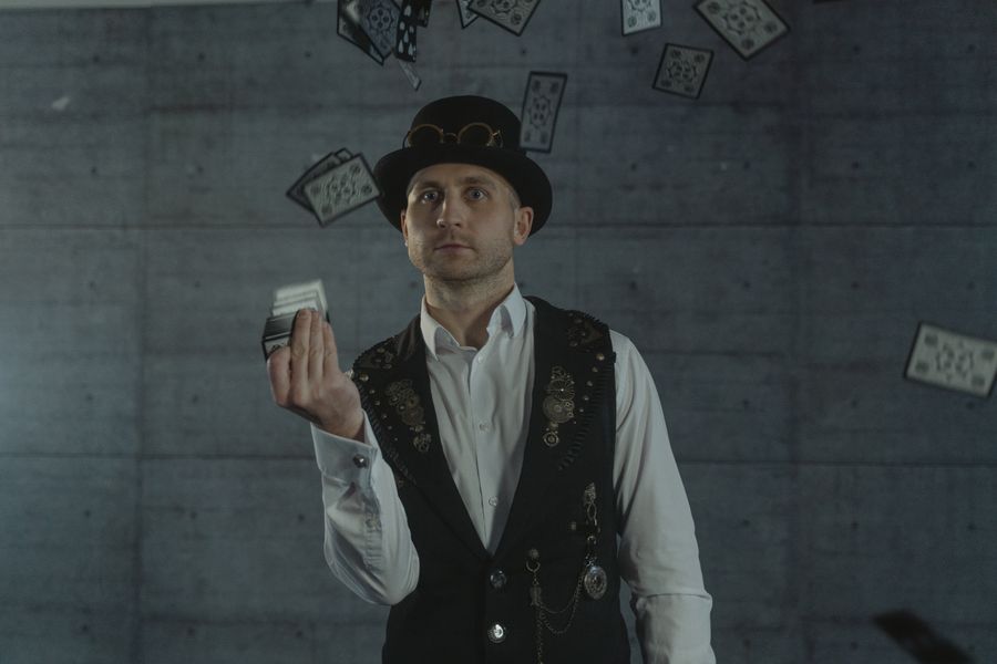 A magician in steampunk style performing an impressive card trick indoors.