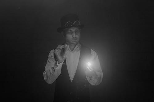 Grayscale Photo of a Man Doing a Magic Trick
