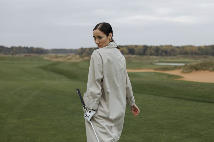 Back View Of A Female Golfer Walking On Golf Field