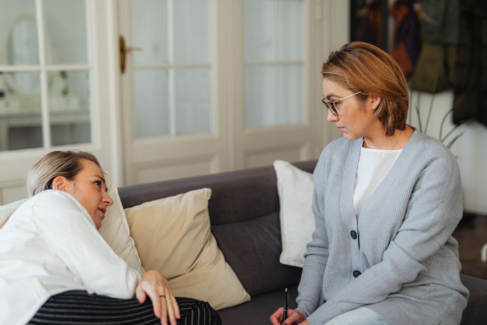 A therapist attentively listens to a client during a counseling session in a cozy indoor setting.
