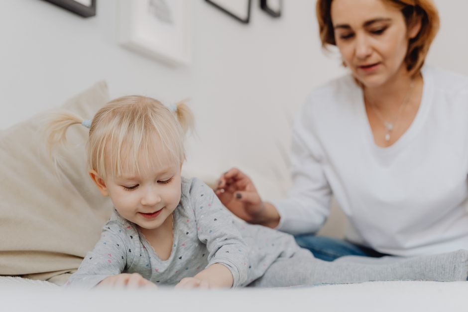 Photo by https://kaboompics.com/ on Pexels A smiling toddler with pigtails playing indoors with her mother watching. - Photo by https://kaboompics.com/ on Pexels