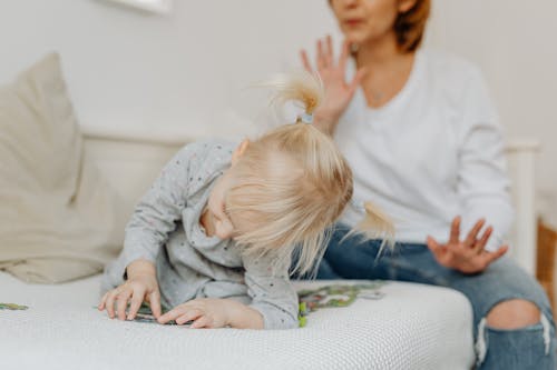 Free Woman on Couch and Daughter Playing with Puzzles Stock Photo