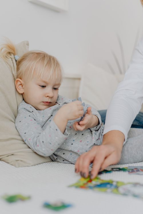 Free Young child engaging in a puzzle activity while relaxing indoors. Stock Photo