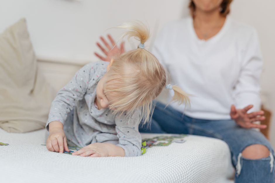 A mother and her young daughter enjoy playtime together indoors, focusing on the child's curiosity.