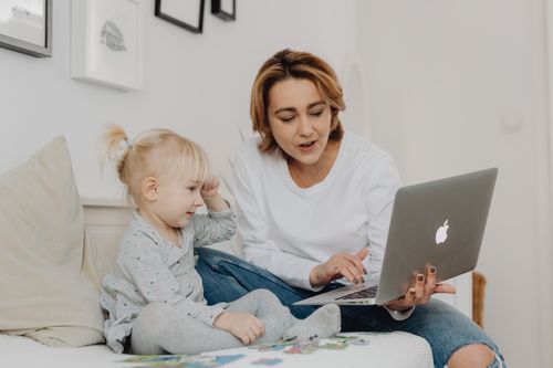 Free Mother and daughter sitting together using a laptop in a cozy home setting. Stock Photo