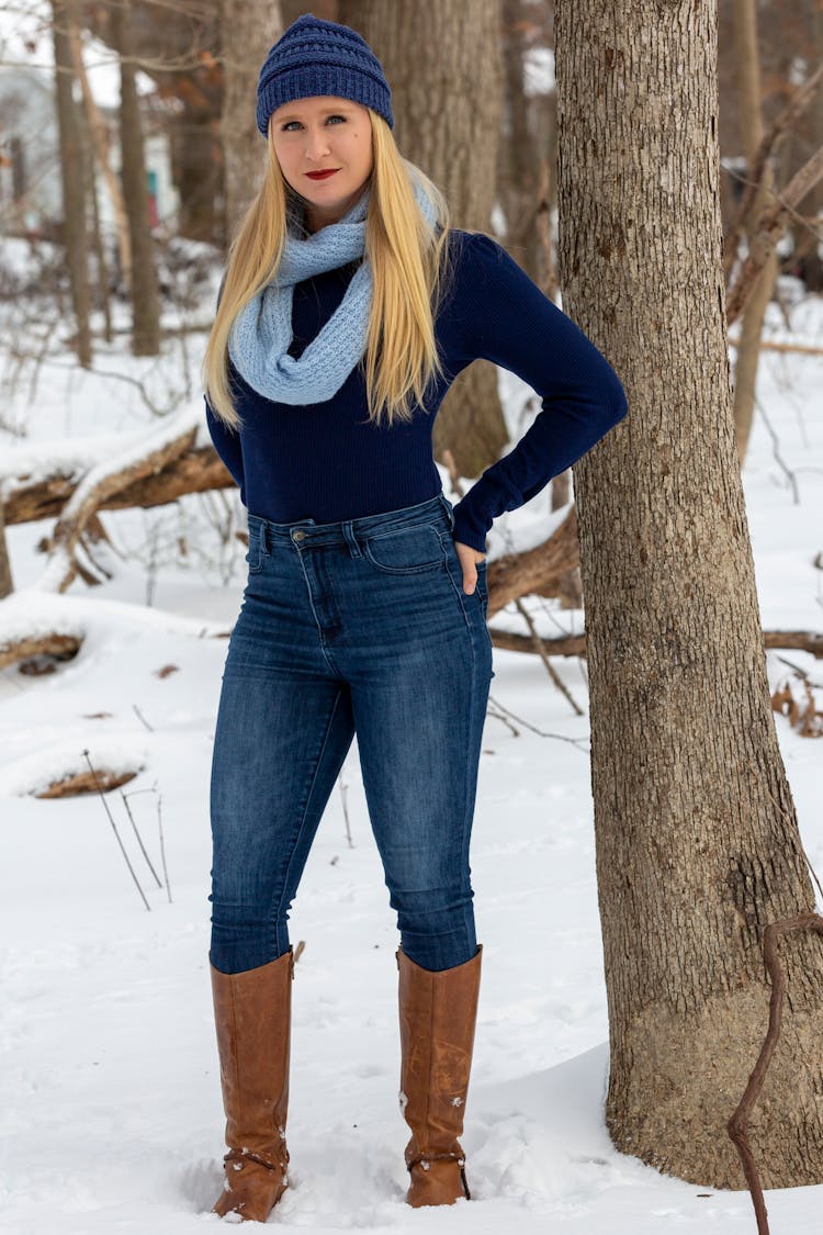 Content Woman In Hat Standing In Winter Forest