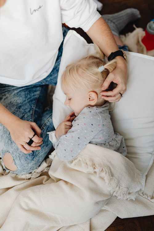 Free A mother lovingly comforts her sleeping child, capturing a serene family moment indoors. Stock Photo