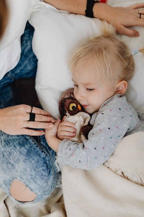 Free A young child relaxing indoors, hugging a stuffed animal with a sense of comfort and warmth. Stock Photo