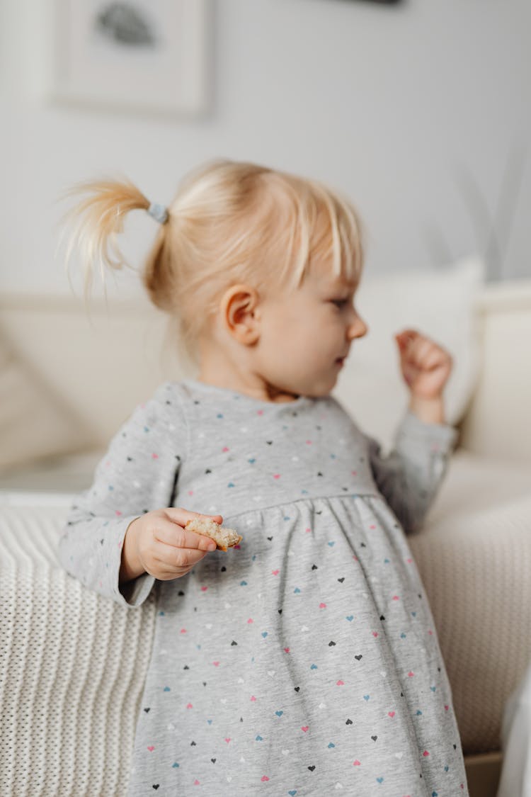 A Girl In A Dress Eating Bread