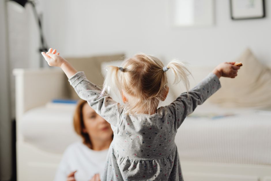 Cute child with raised arms indoors at home in a playful moment.