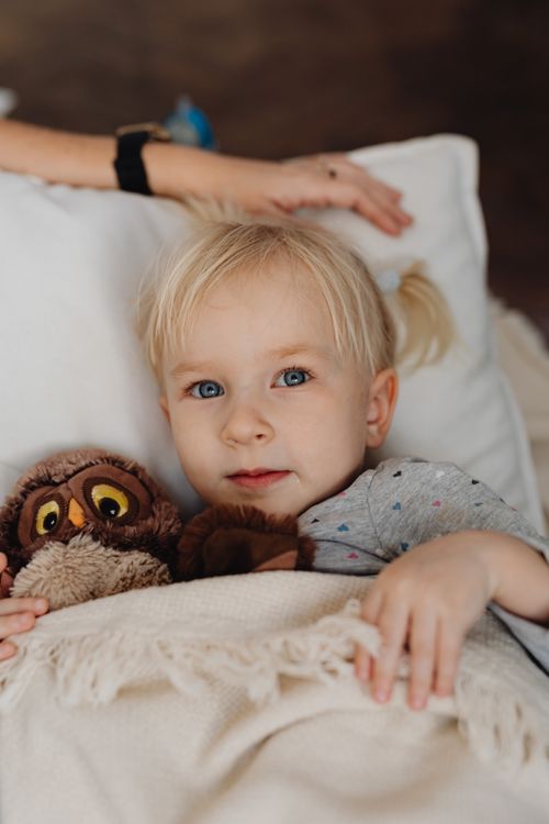 Free Cute child holding an owl plush toy in bed, creating a cozy scene. Stock Photo