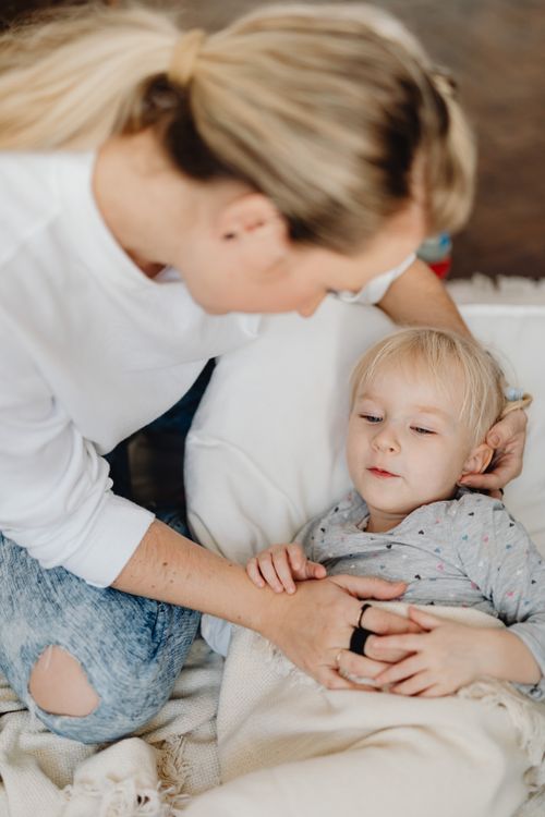 Free A nurturing mother takes care of her child who is comfortably resting indoors during the day. Stock Photo