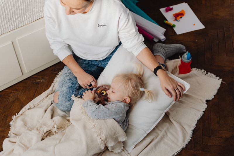 A mother gently comforts her sleeping daughter, creating a warm and nurturing atmosphere.