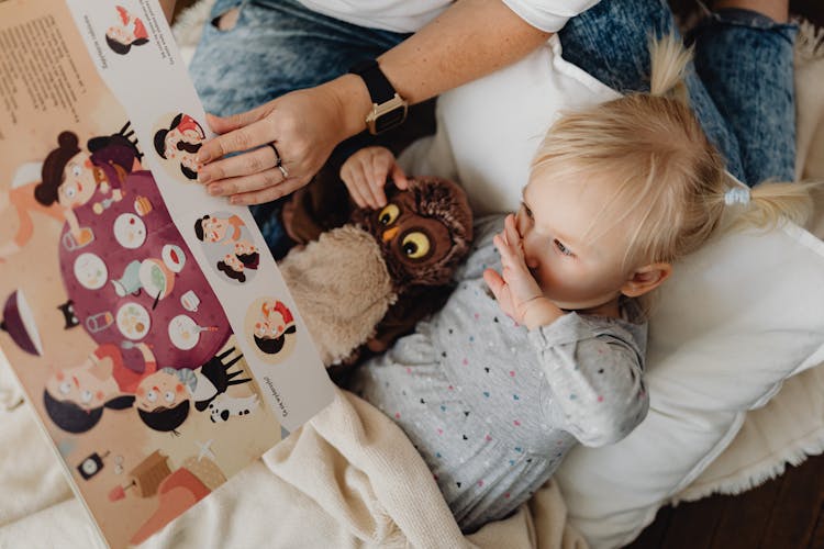 A Girl Lying Down While Reading A Storybook