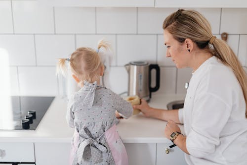 Mom Looking at Her Daughter While Leaning on Kitchen Counter