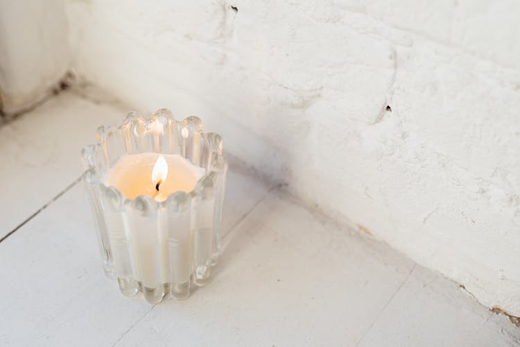 Burning Candle In A Glass Jar On The Floor