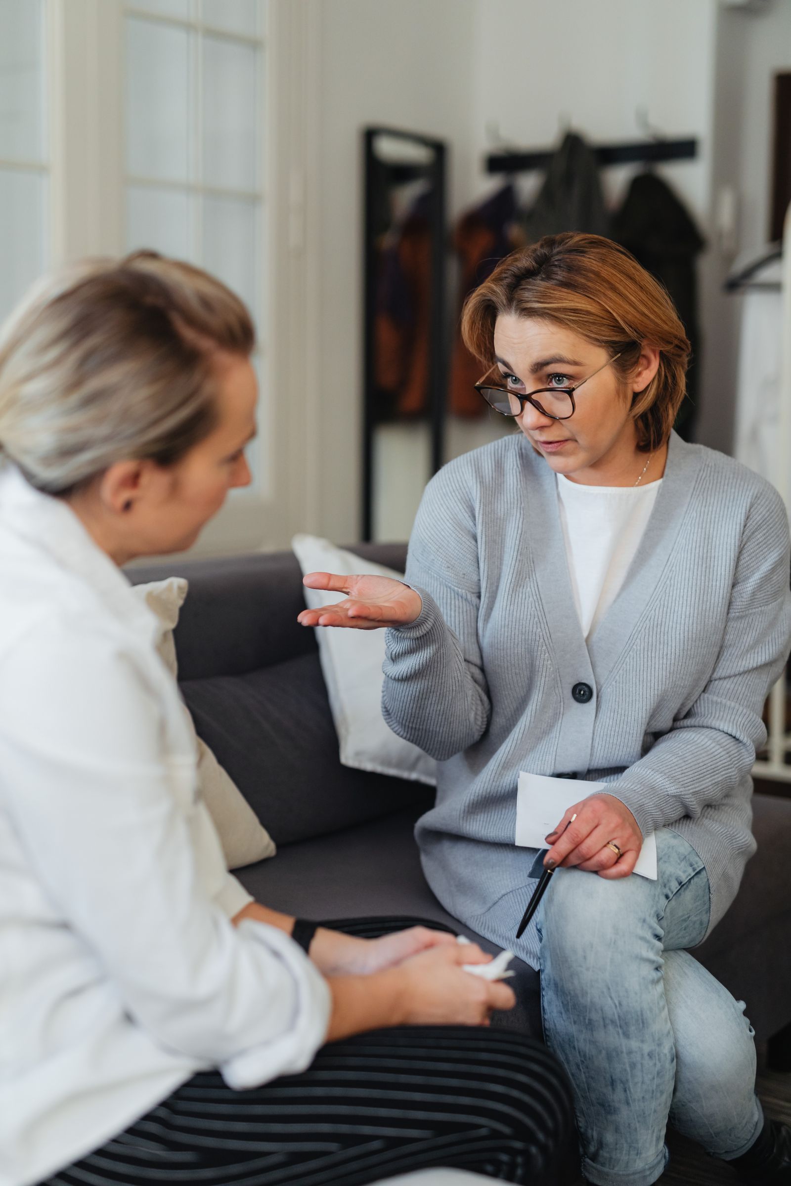 Two adult women having a private supportive conversation on a couch