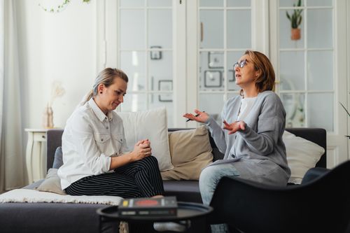 Free Two women having a conversation in a bright, cozy living room. Stock Photo
