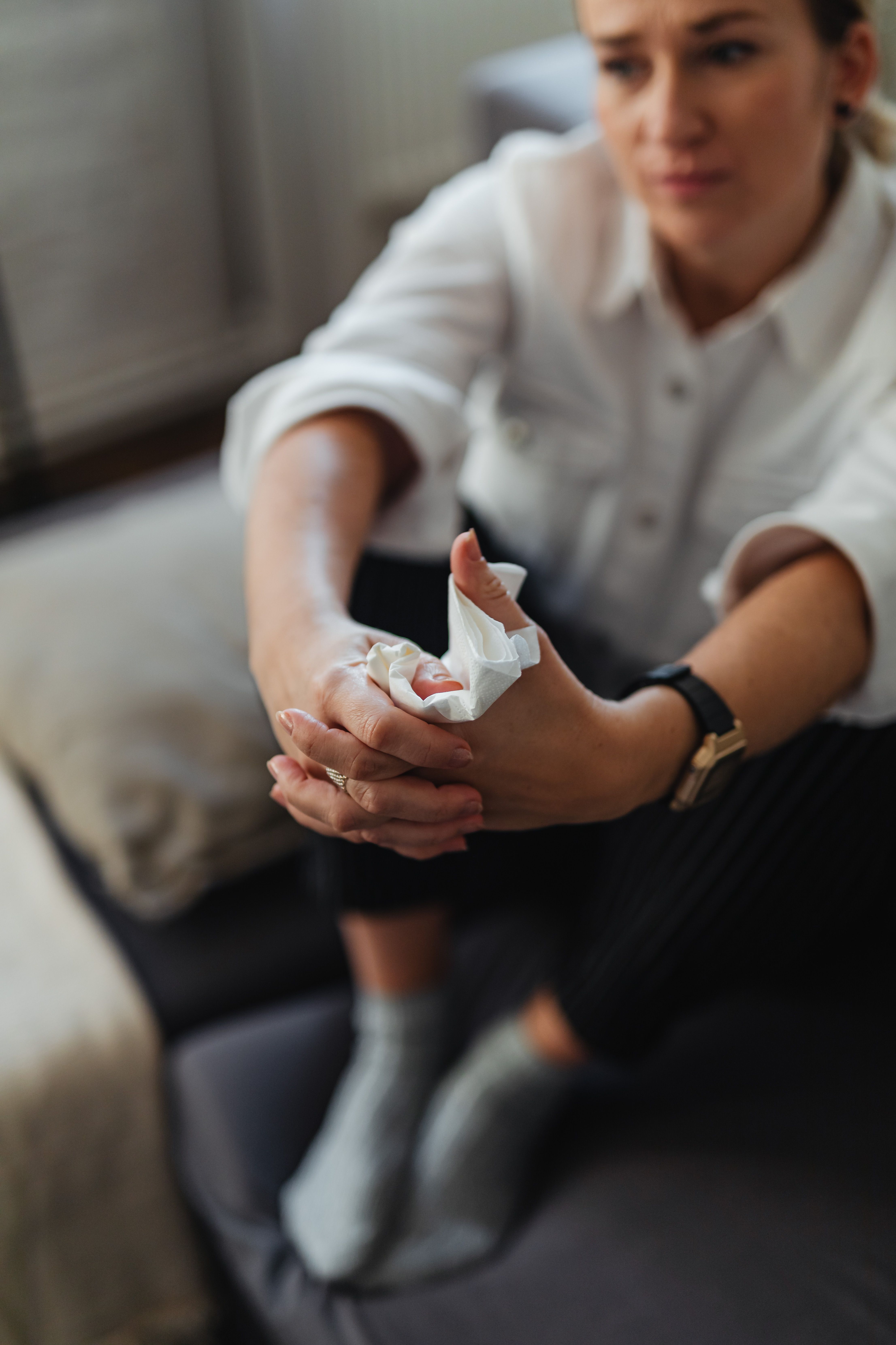 Close-up of a woman indoors holding a tissue, appearing thoughtful and introspective.