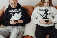 Young Man and Woman in Hoodie Sweaters Using Cellphone
