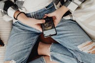 Person in Ripped Denim Jeans Using Cellphone