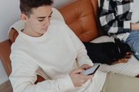 Young Man in White Long Sleeve Shirt Using Cellphone