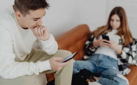 Dos adolescentes en un sofá mirando el móvil