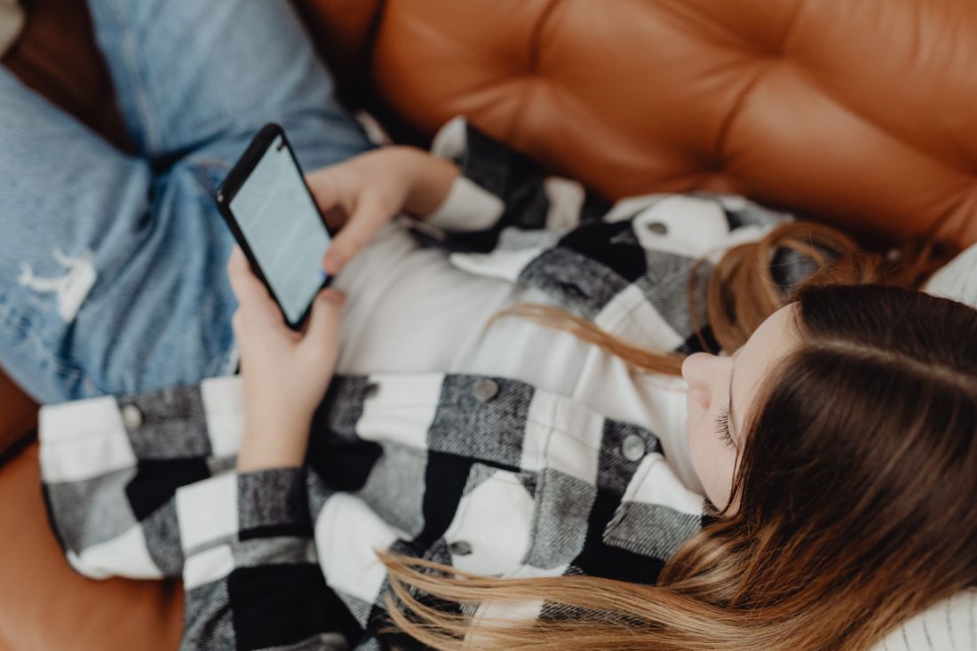 A teenage girl lying on the bed using her phone