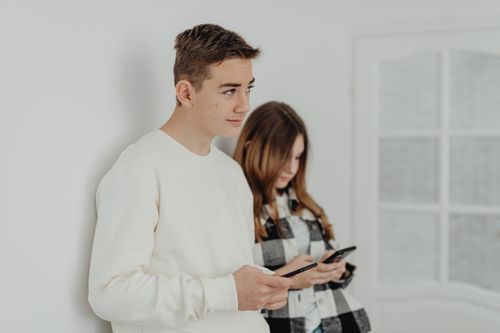 Free Two teenagers using smartphones, focusing on communication indoors. Stock Photo