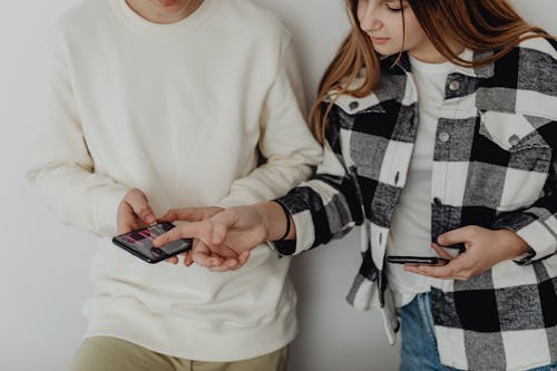 Free Young Couple Looking at Their Smart Phones  Stock Photo