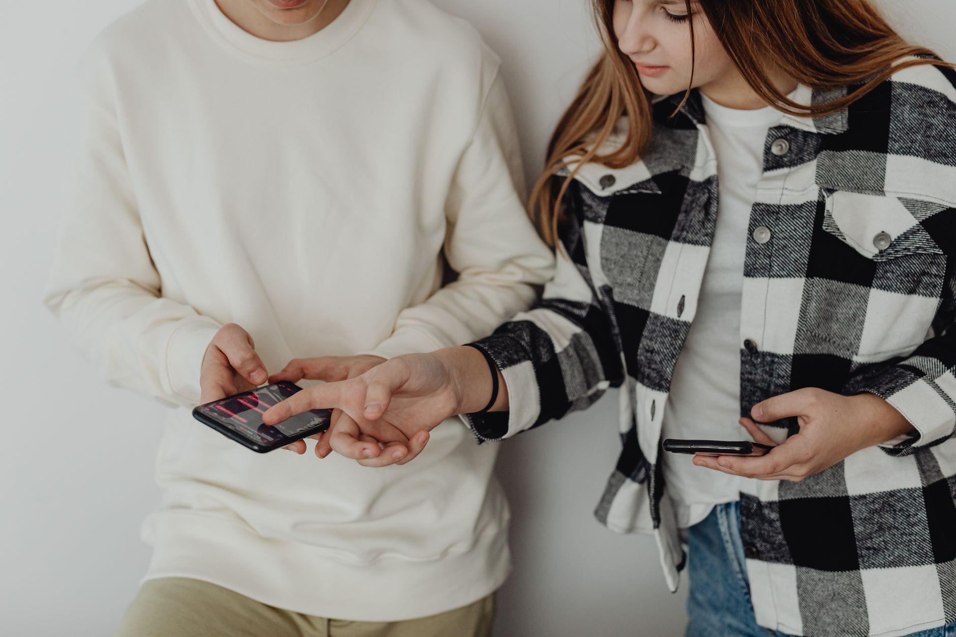 Two teenagers checking the same phone, the modern version of comparing notes on what a relationship is supposed to look like.