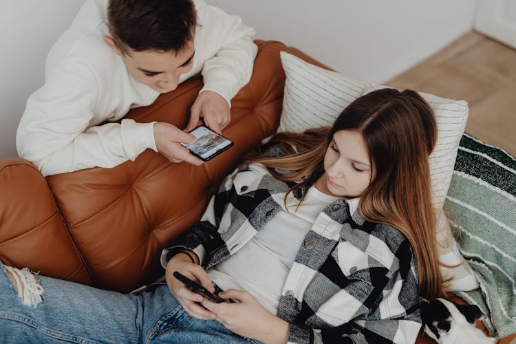 A Boy And A Girl Using Smart Phones In The Living Room