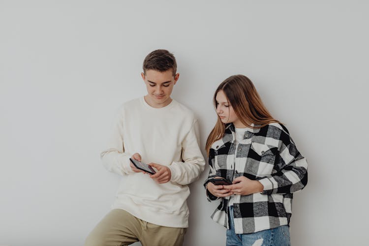 Studio Portrait Of Two Teenagers With Phones