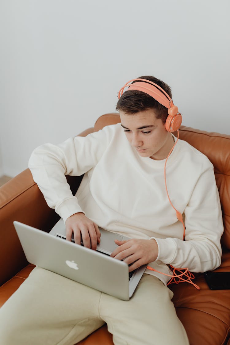 Young Man Wearing Headphones Using Laptop