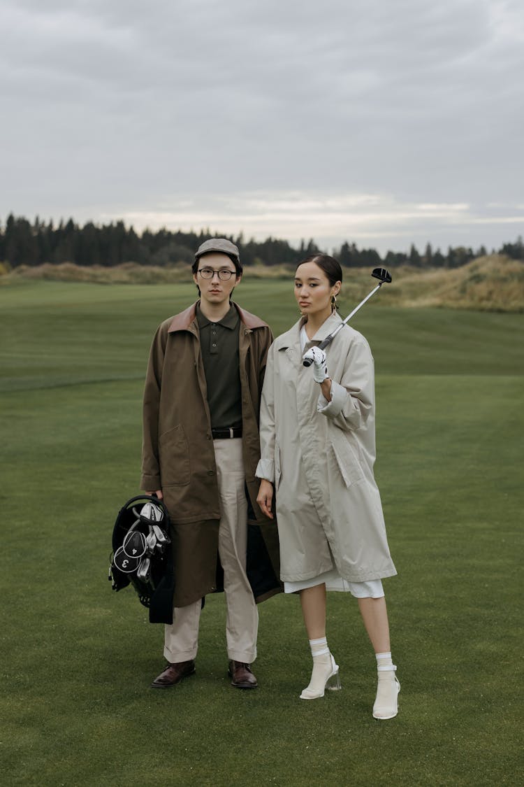 A Man And Woman Holding Golf Club Together 