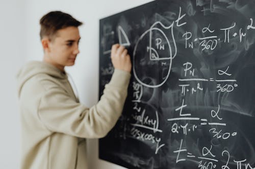 Boy Solving an Equation on a Blackboard 