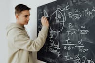 Boy Solving an Equation on a Blackboard