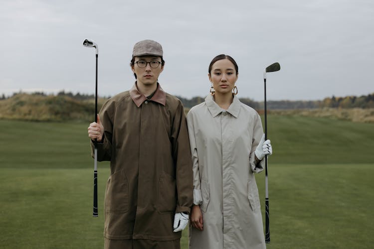 Close-Up Shot Of A Man And Woman Holding Golf Clubs