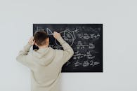 Boy in Beige Hoodie Solving a Math Problem