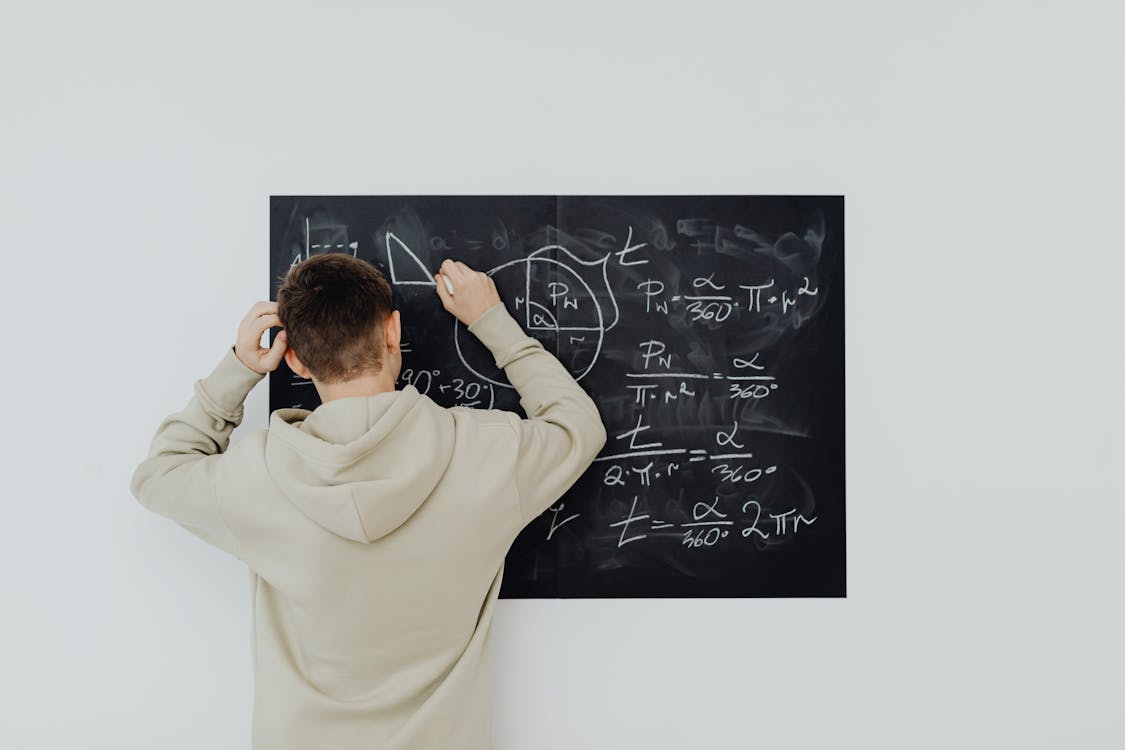 Free Boy in Beige Hoodie Solving a Math Problem Stock Photo