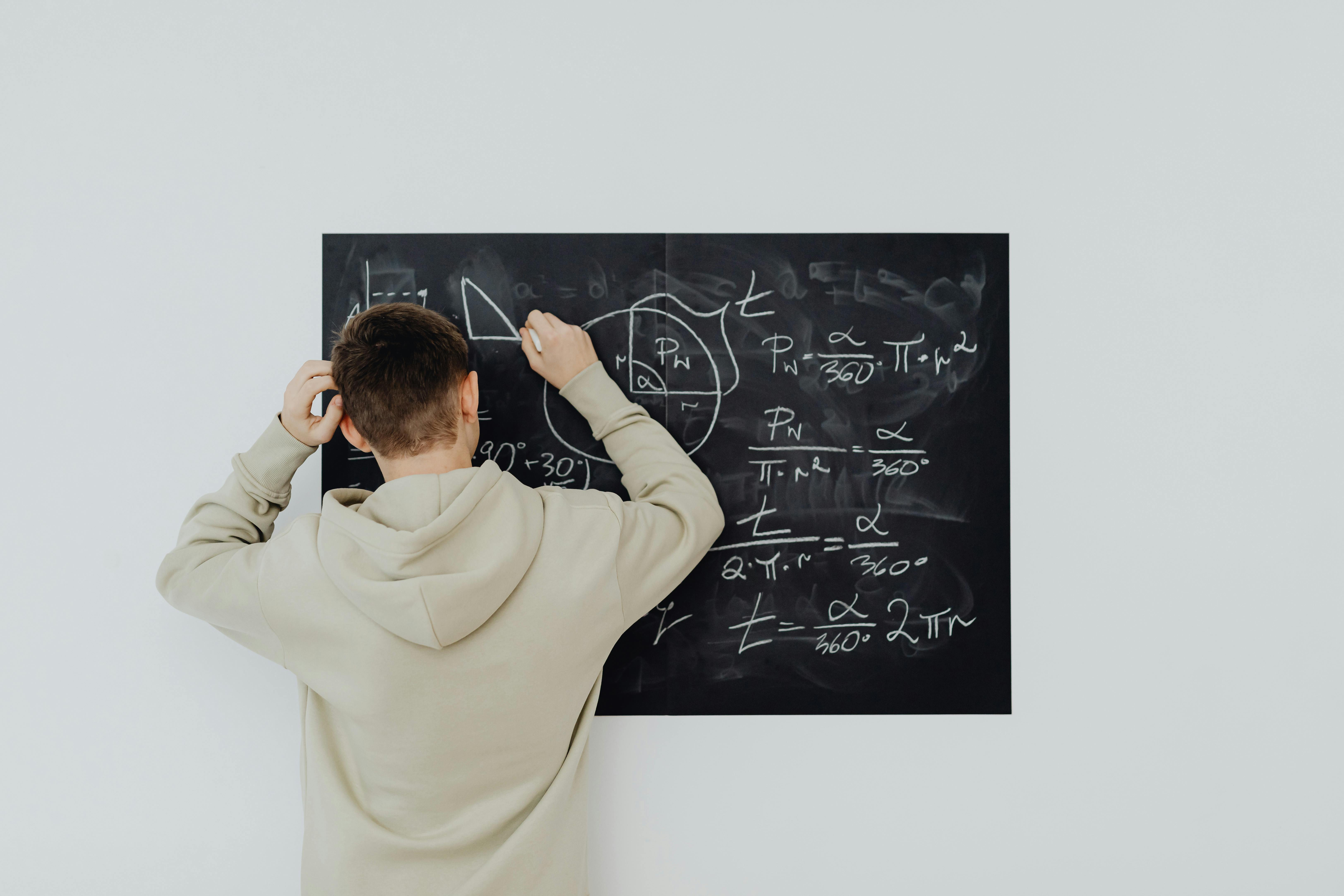 Boy in Beige Hoodie Solving a Math Problem