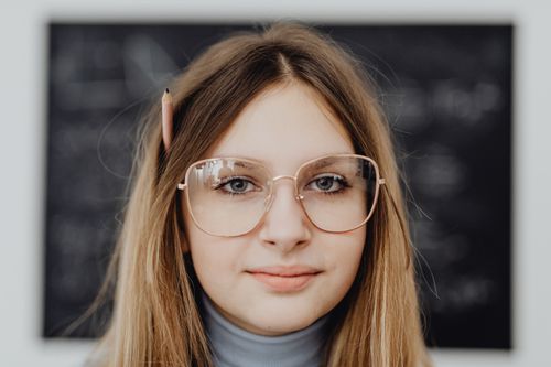 Free Close-up portrait of a teenage girl with eyeglasses and pencil in hair. Stock Photo