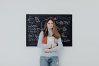 Teenage Girl Standing in front of the Blackboard Holding Notebooks