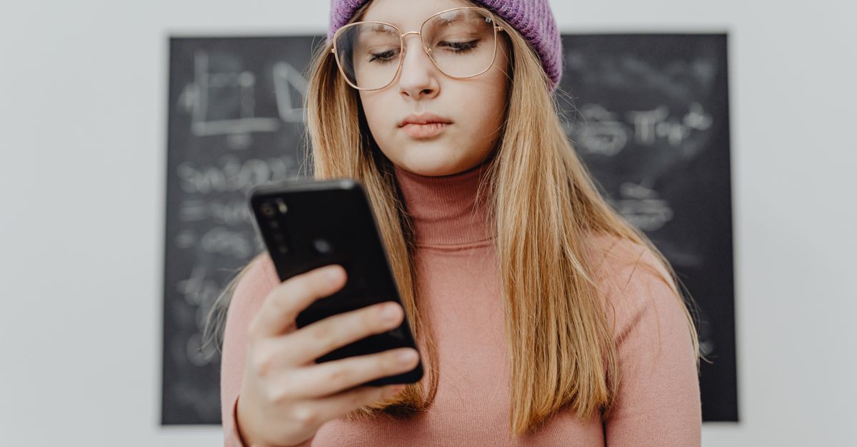 Gen Z person looking at phone with a stained-glass window reflection on the screen