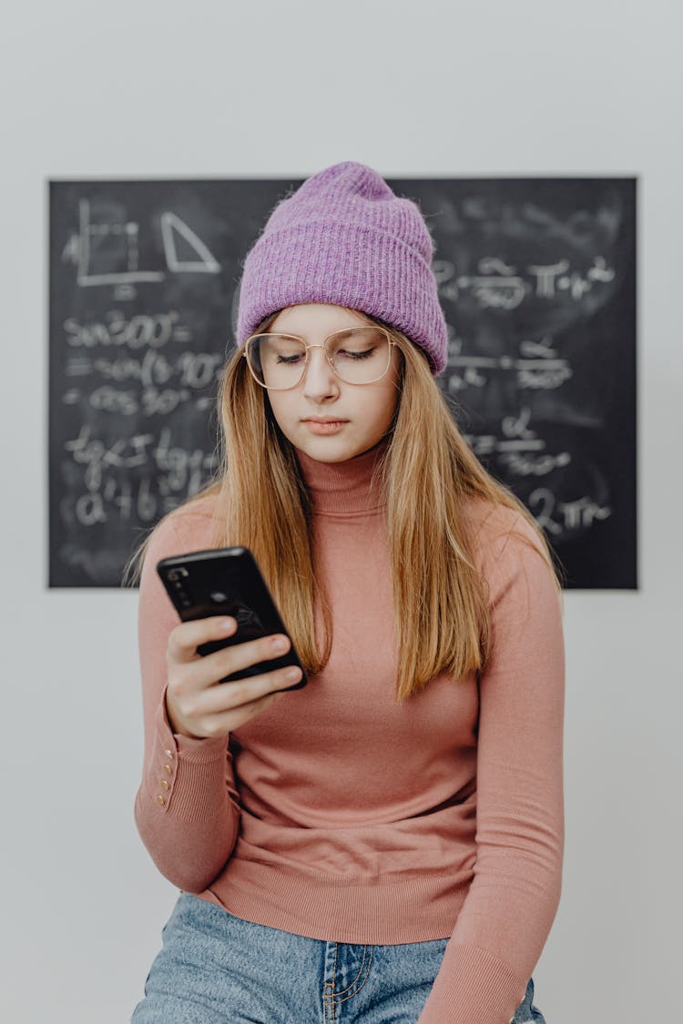 Girl Standing In Front Of A Blackboard And Holding A Phone